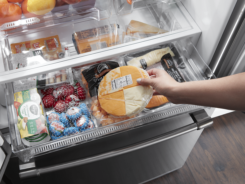 A person taking cheese out of a fridge drawer