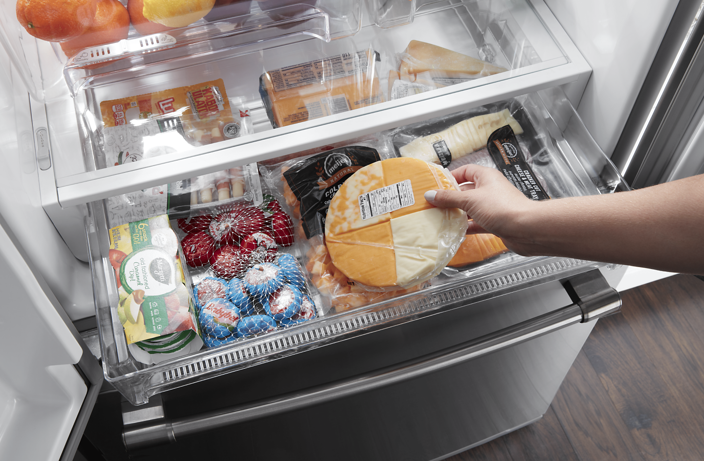 A person taking cheese out of a fridge drawer