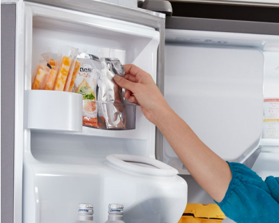 A person storing items in a fridge door shelf