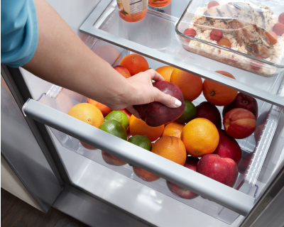 A person storing apples in a fridge crisper drawer