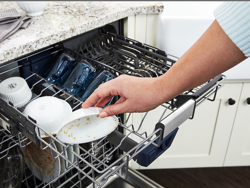 Person loading a dirty bowl into a dishwasher.