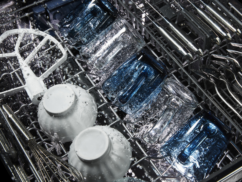 Glasses, bowls and silverware being cleaned in a dishwasher.