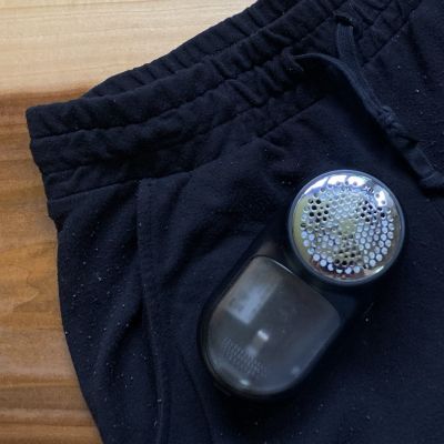 A fabric shaver on a pair sweatpants with fabric pilling