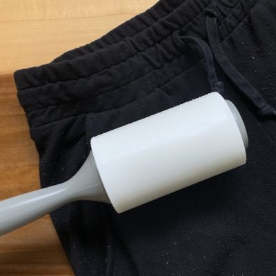 A lint roller on a pair of sweatpants with pilling