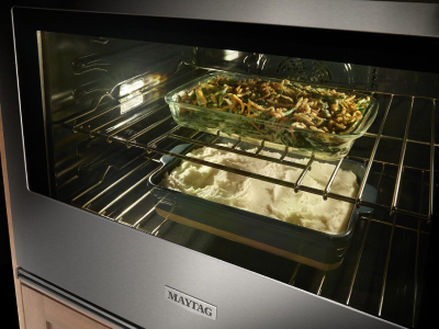 Pans of food cooking on racks of a Maytag® oven