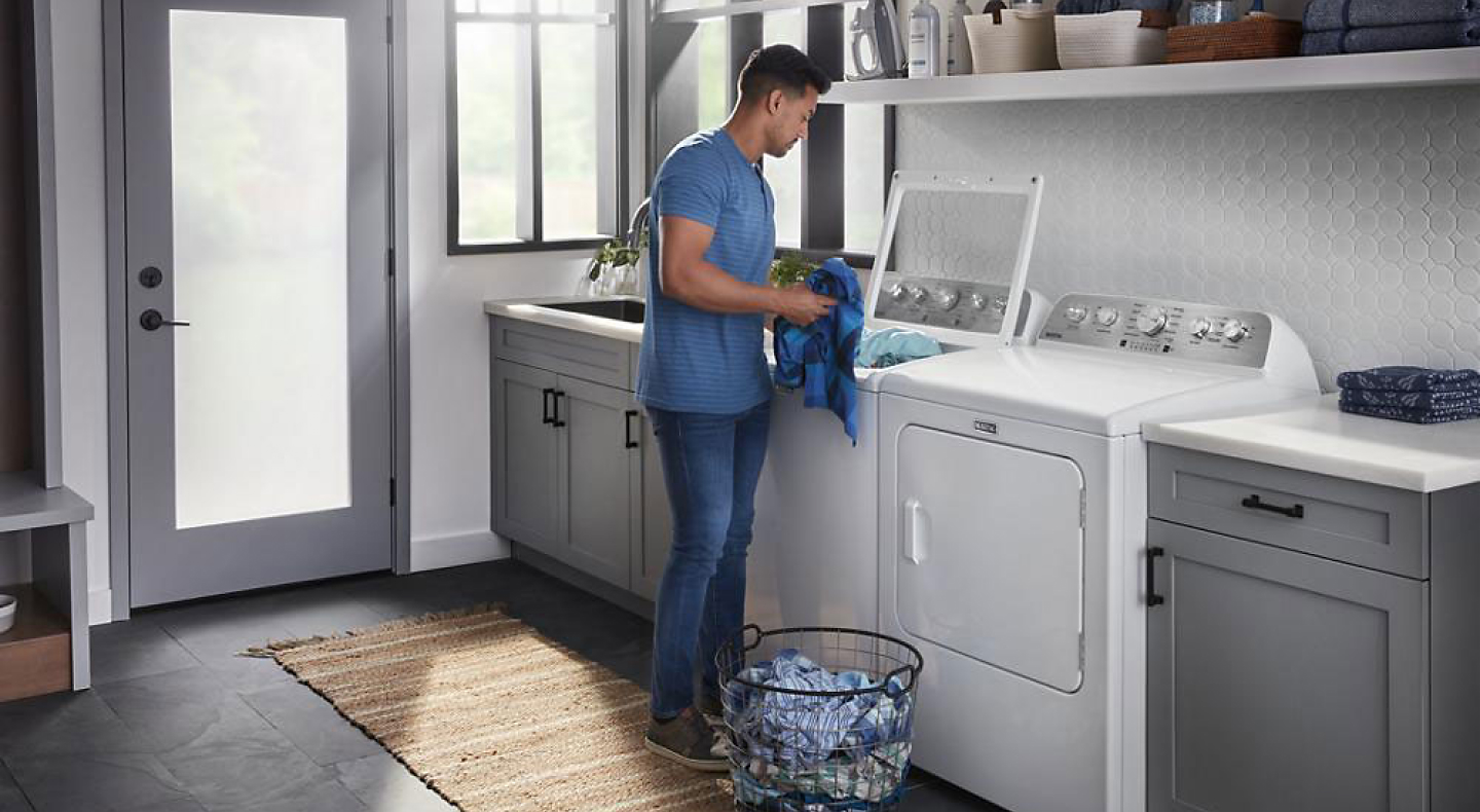 Person placing clothes into a top load washing machine