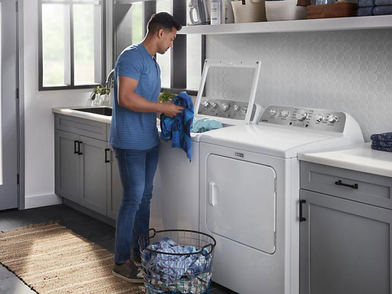 Person placing clothes into a top load washing machine