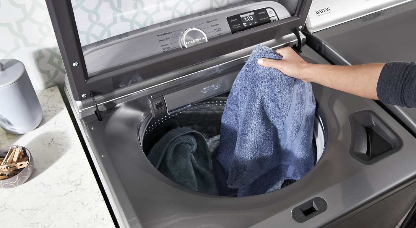 Person placing a towel in a washing machine Person placing a towel in a washing machine