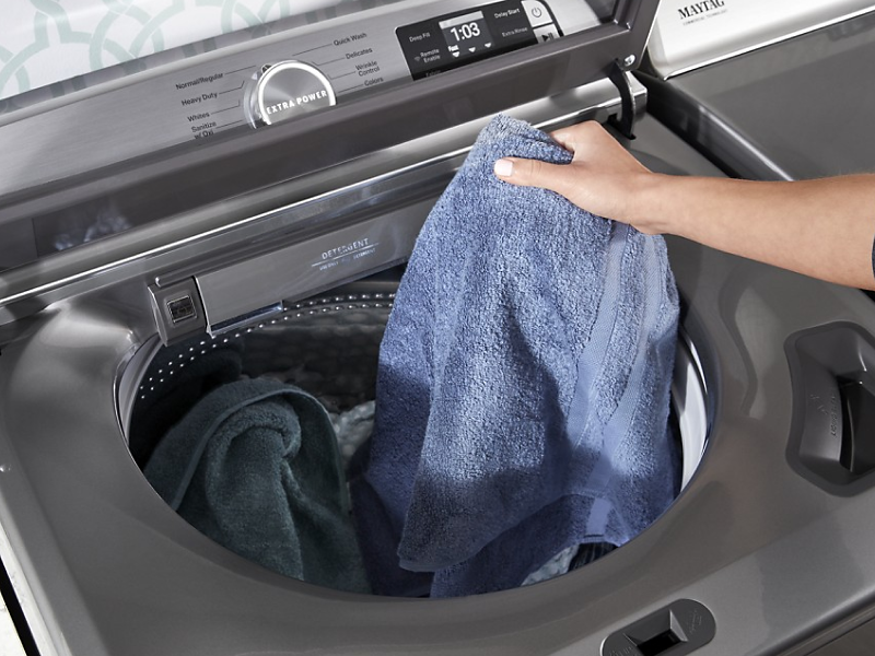 Person placing a towel in a washing machine