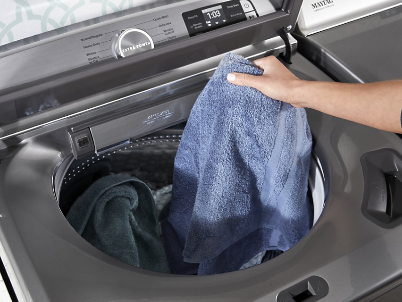 Person placing a towel in a washing machine Person placing a towel in a washing machine