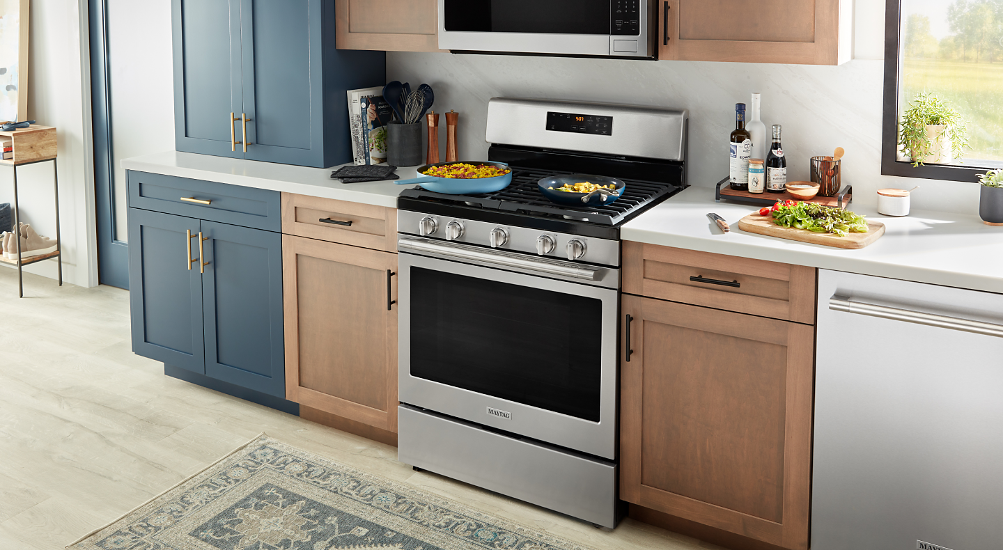 A Maytag® gas range with frying pans on the cooktop in a modern kitchen