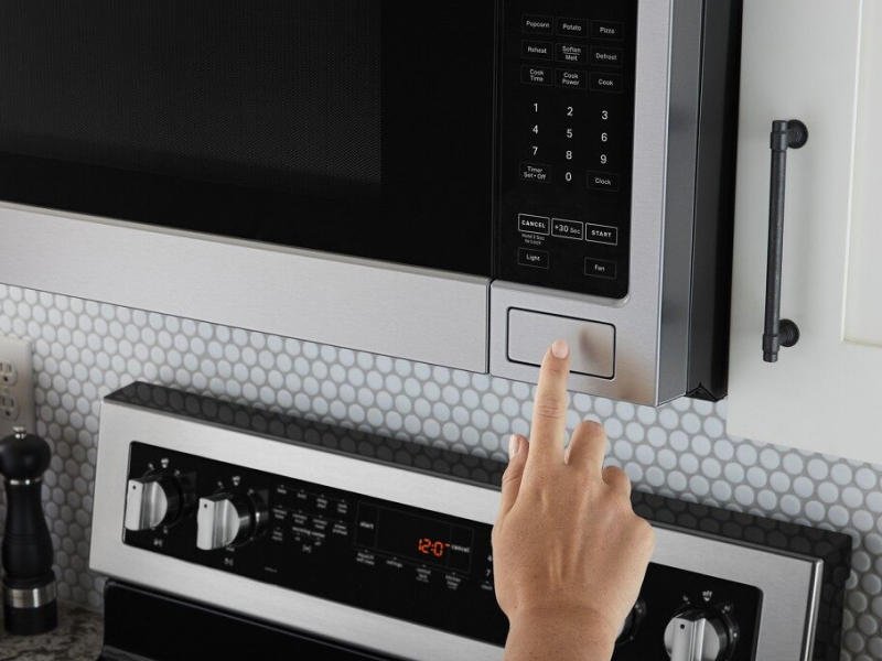 A closeup of a person programming a Maytag® microwave