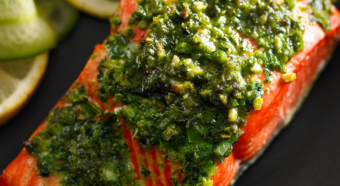 Closeup of cooked fish garnished with pesto