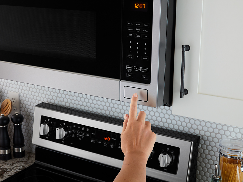 Person pressing open button on microwave