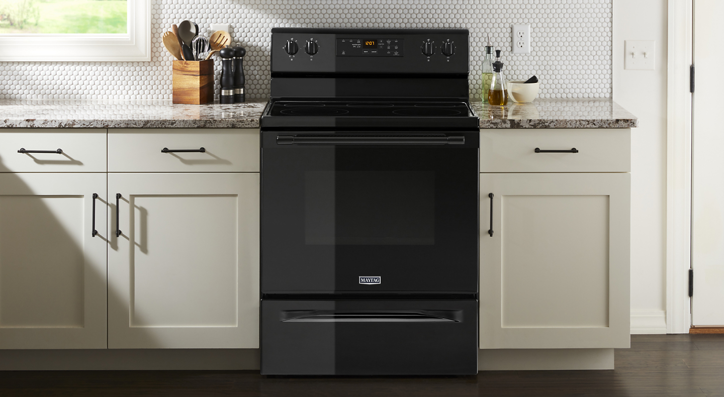 Black electric oven from Maytag brand in cream colored cabinetry
