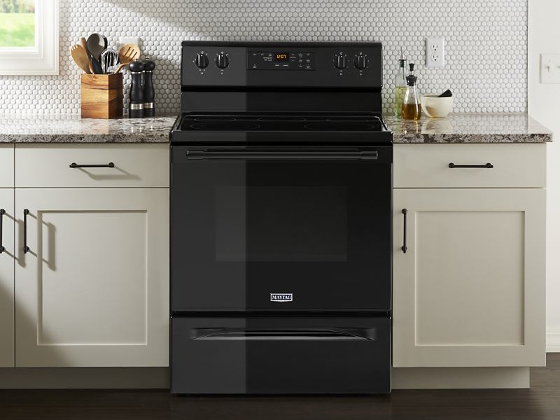Black electric oven from Maytag brand in cream colored cabinetry