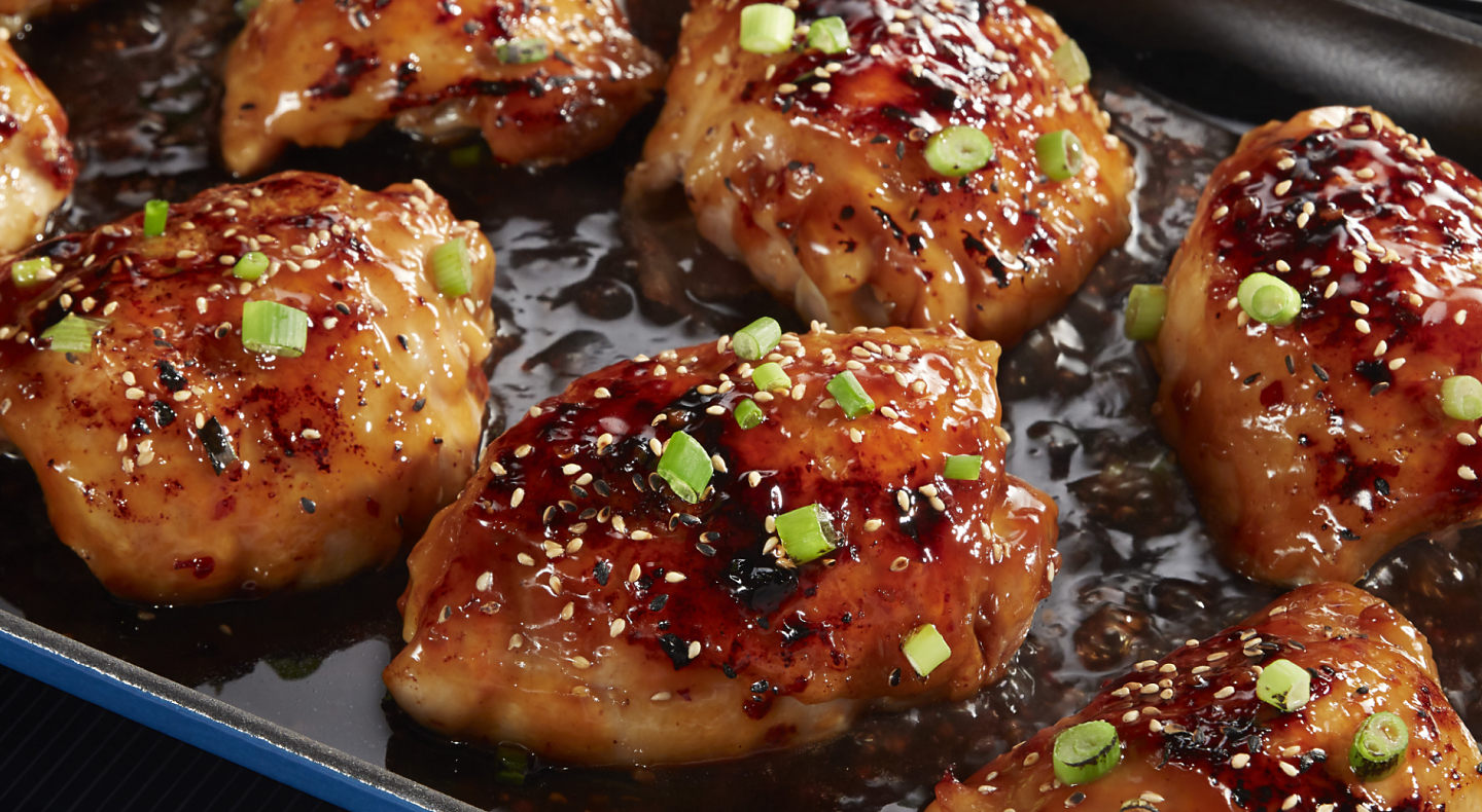 Close-up of teriyaki chicken sprinkled with sesame seeds and green onions