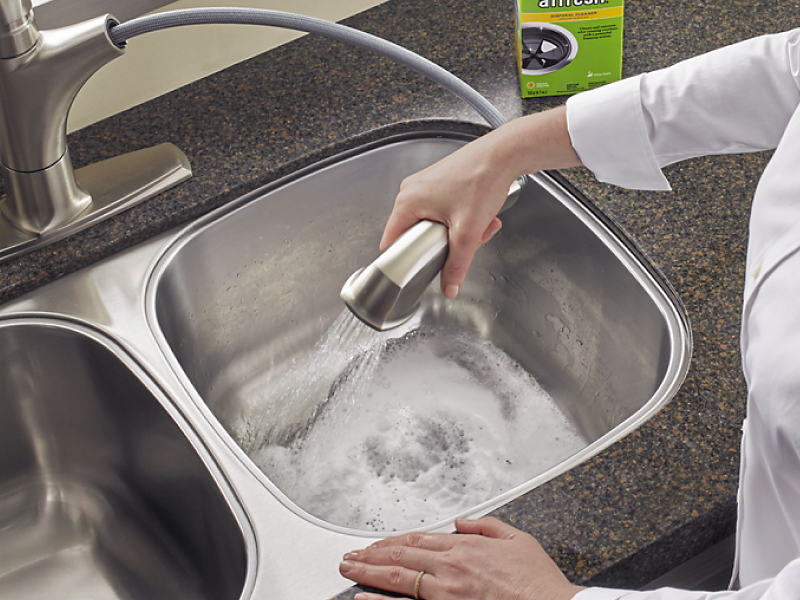 A person rinsing foam from an affresh® disposal cleaner tablet down the drain