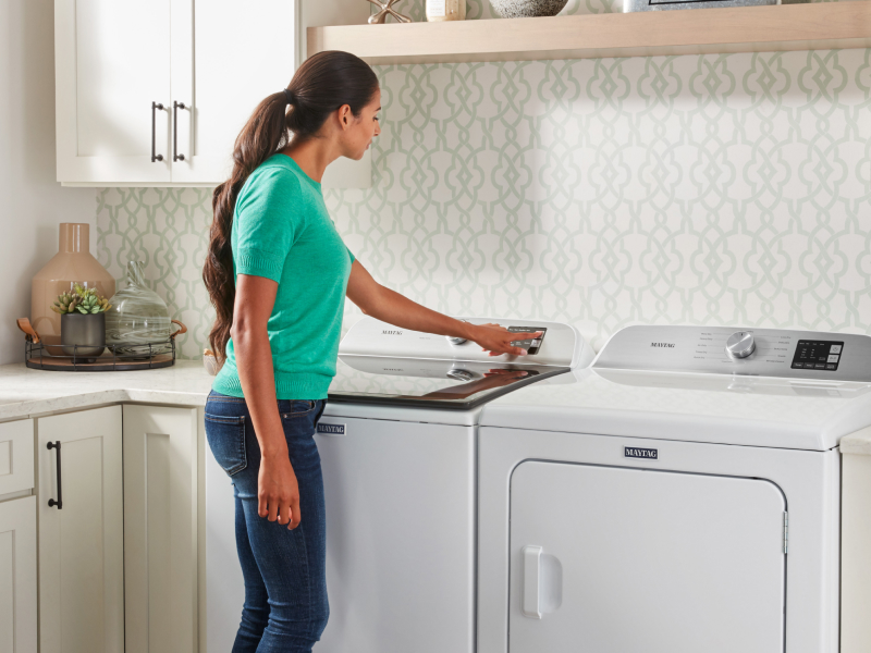 Person selecting a cycle on Maytag® washing machine