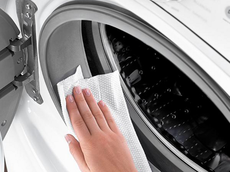 Person wiping door gasket on washing machine