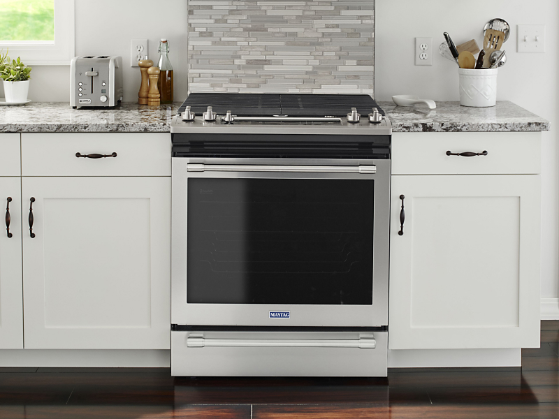 A stainless steel oven surrounded by white cabinetry
