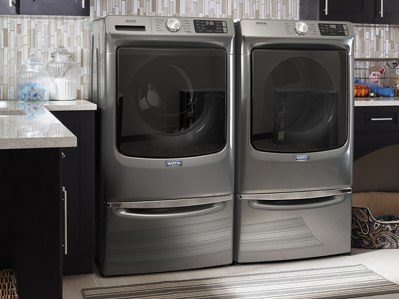 Metallic slate Maytag® front load washer and dryer set in a laundry room