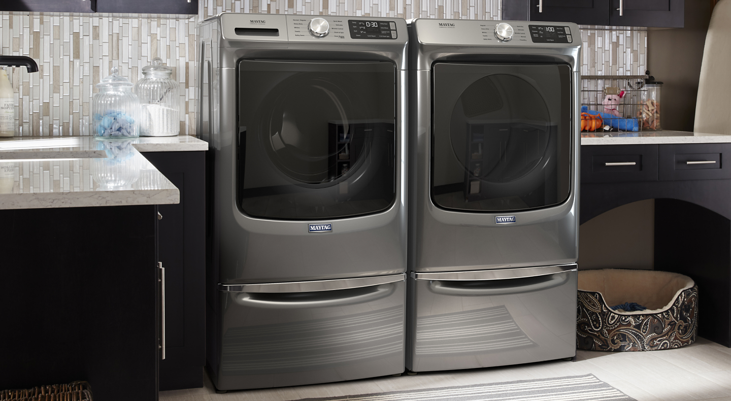 Metallic slate Maytag® front load washer and dryer set in a laundry room