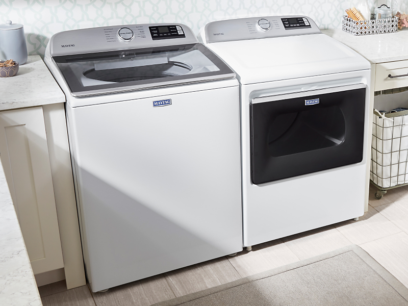 White Maytag® top load washer and dryer set in a bright laundry room