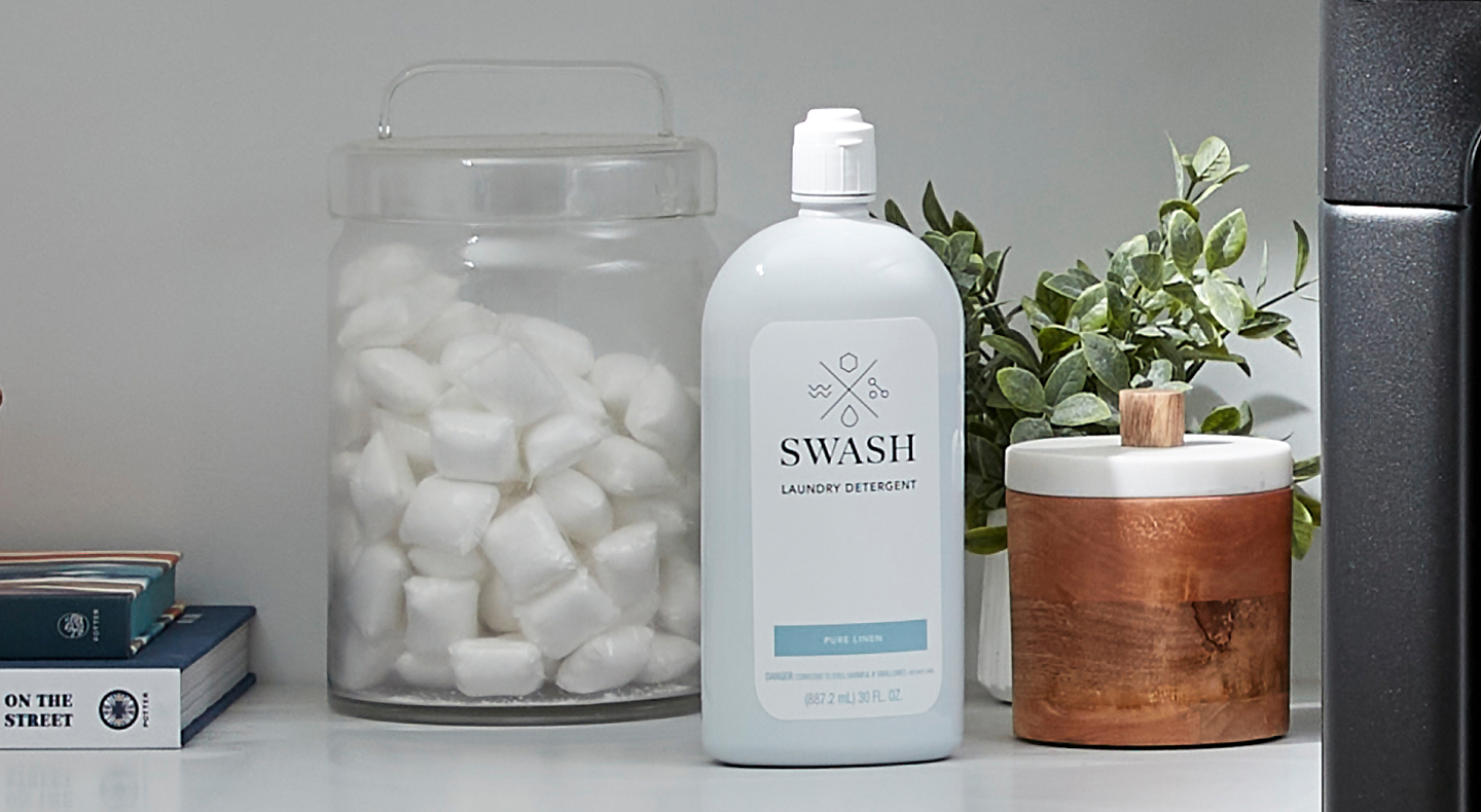 Swash® detergent next to a glass jar of laundry pods