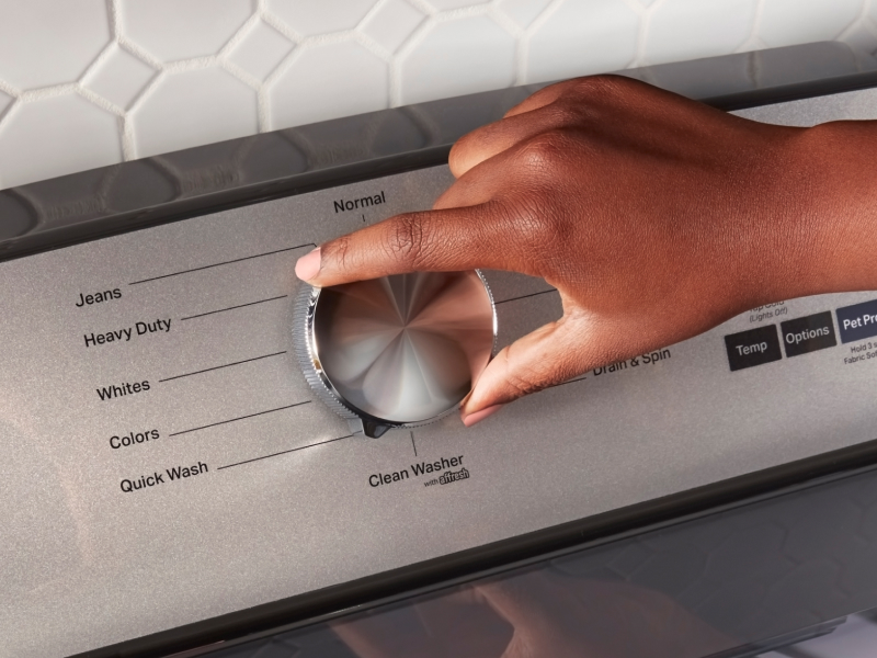 Hand selecting a wash cycle on a Maytag® washing machine