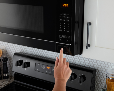 A finger pressing a button to start a microwave