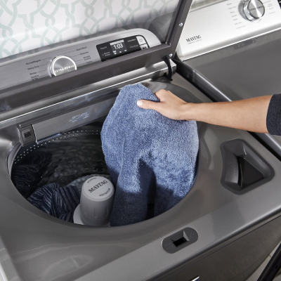 Person loading clothes into Maytag® top load washer 