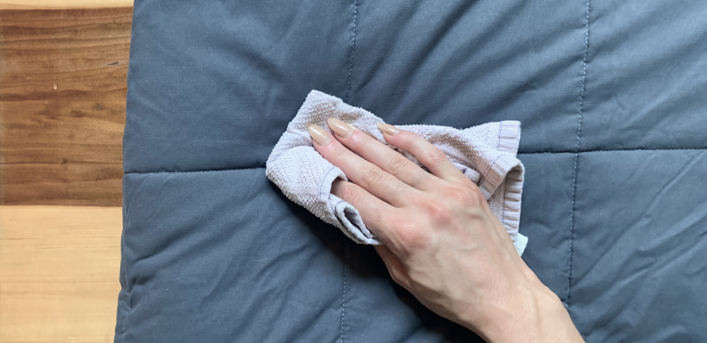 Rag in hand wiping weighted blanket.
