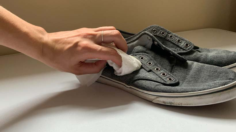 Hand wiping shoes with a clean paper towel