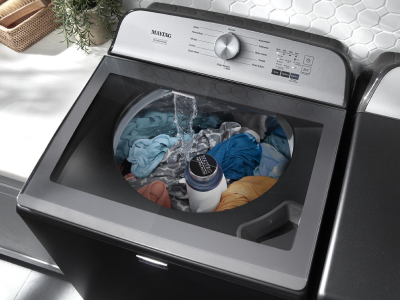 Top load washing machine from Maytag brand with see-through lid and clothes inside agitating