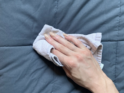 Person wiping blanket with washcloth