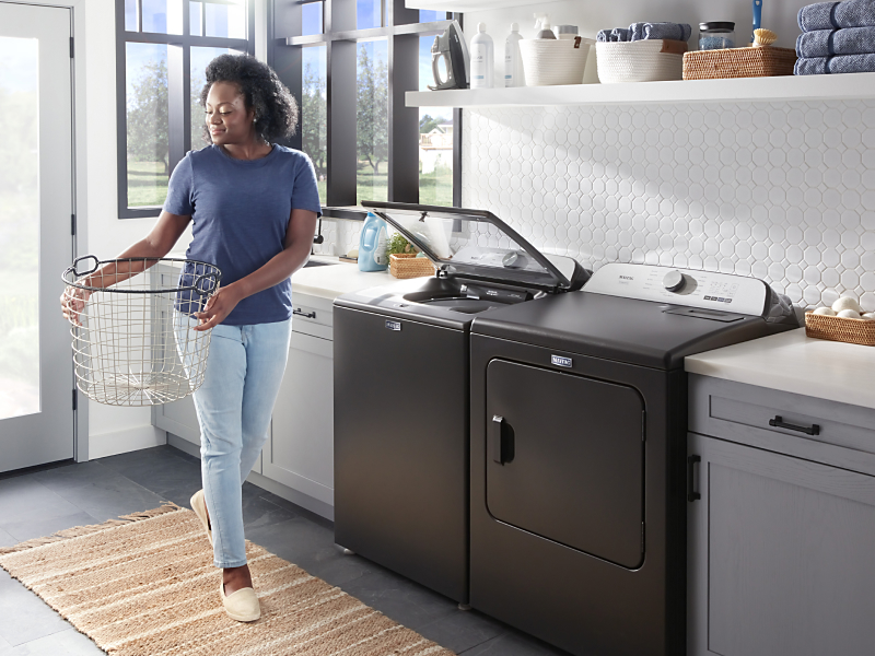Person with laundry basket next to washer and dryer set