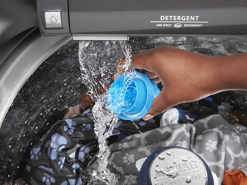 Person adding detergent to a top loading Maytag® washing machine