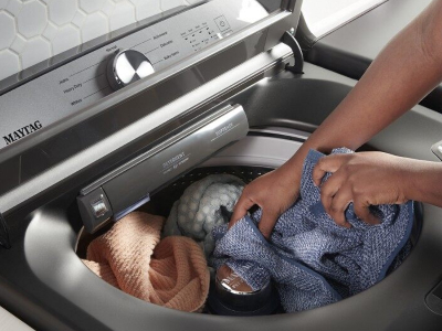Hands loading laundry into the washer
