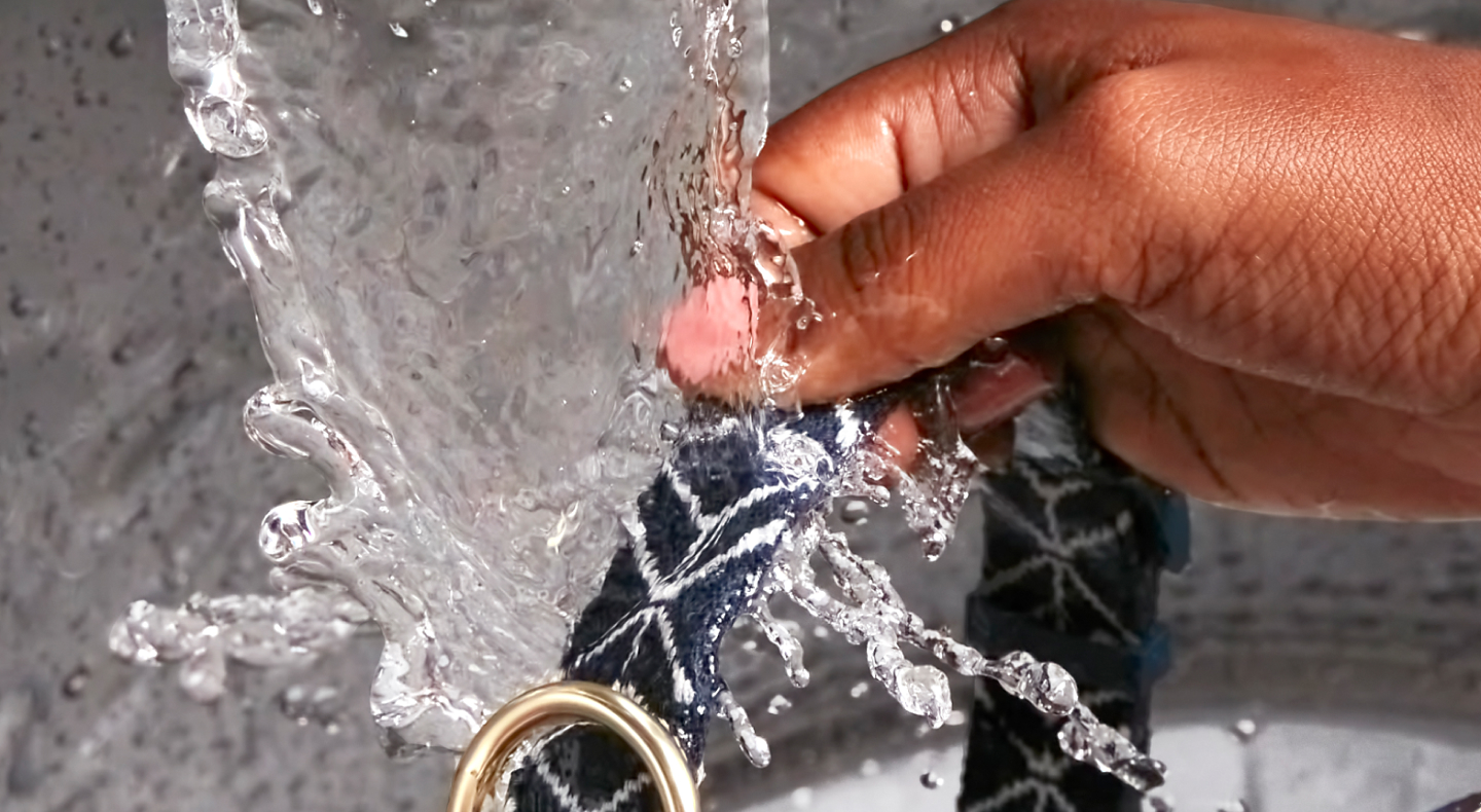 Hand washing a pet collar under running water
