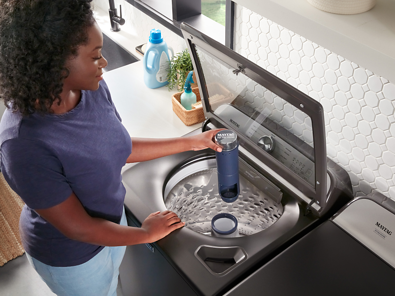 Person loading adding Pet Pro Filter to Maytag® washer