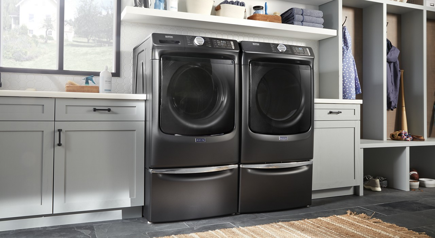 A black Maytag® front load washer and dryer set in a modern laundry room.