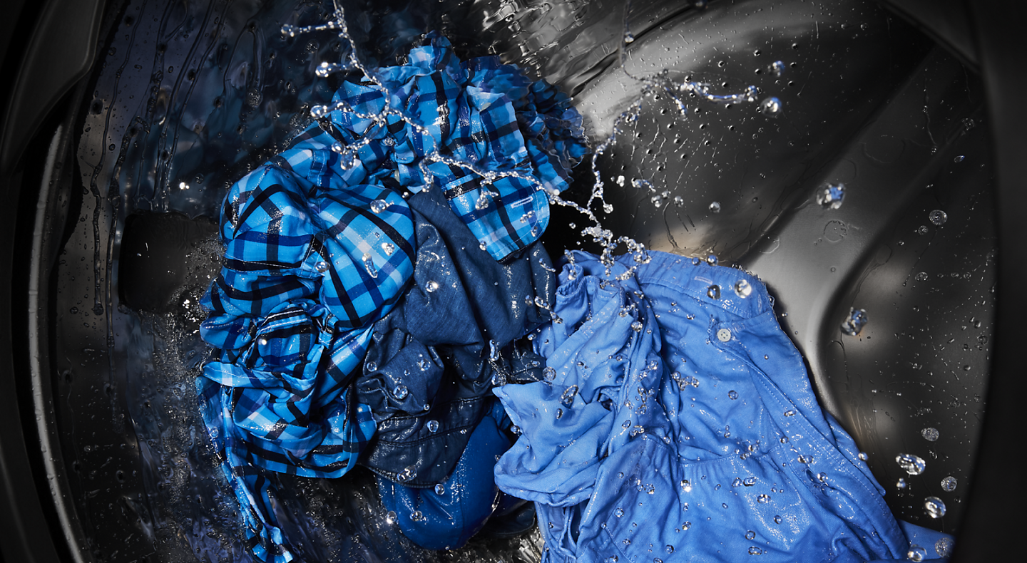 The interior of a Maytag® washer tub washing clothing items.