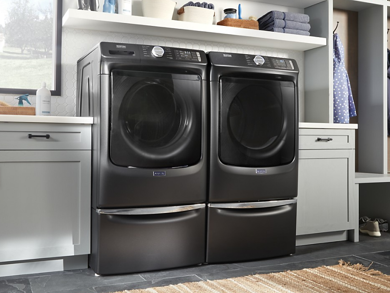 A black Maytag® front load washer and dryer set in a modern laundry room.
