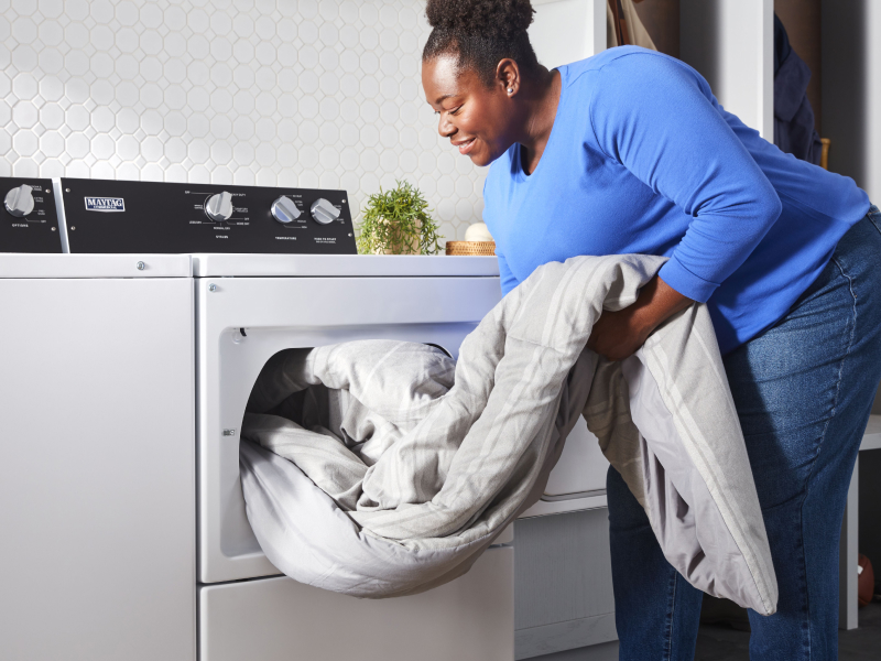 Person loading a down comforter into the dryer.