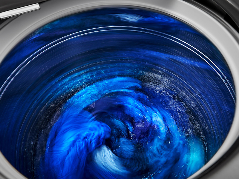Close-up of blue clothes spinning inside washing machine