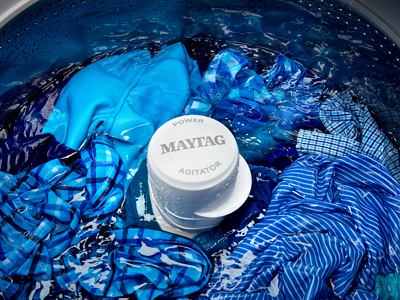 Blue clothes being washed in a Maytag® top-load washing machine