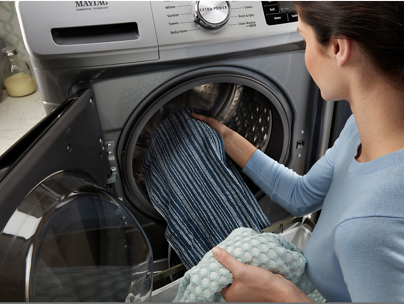 Woman loading towels into a front-load washing machine