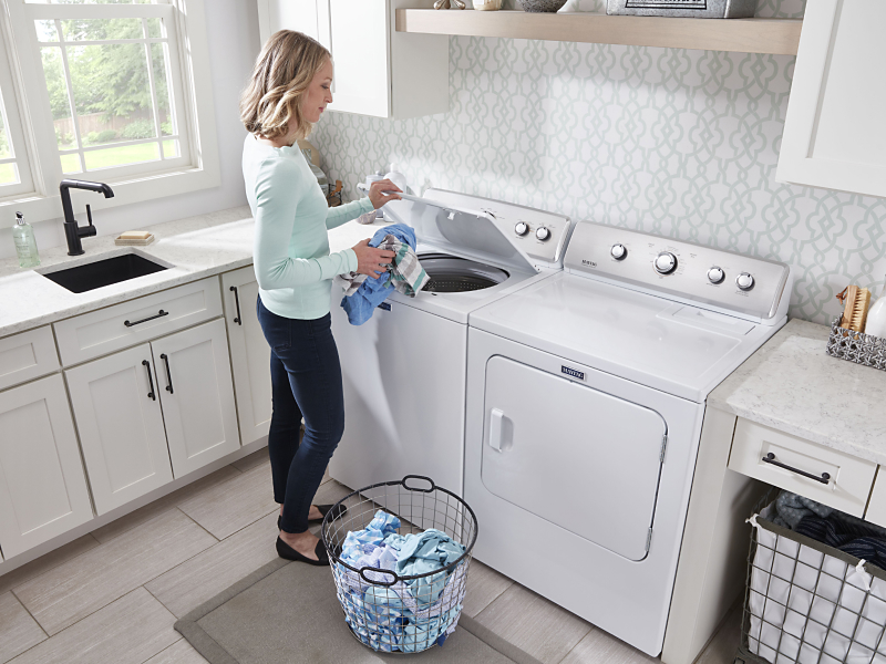 Placing clothes into a Maytag® top-load washing machine