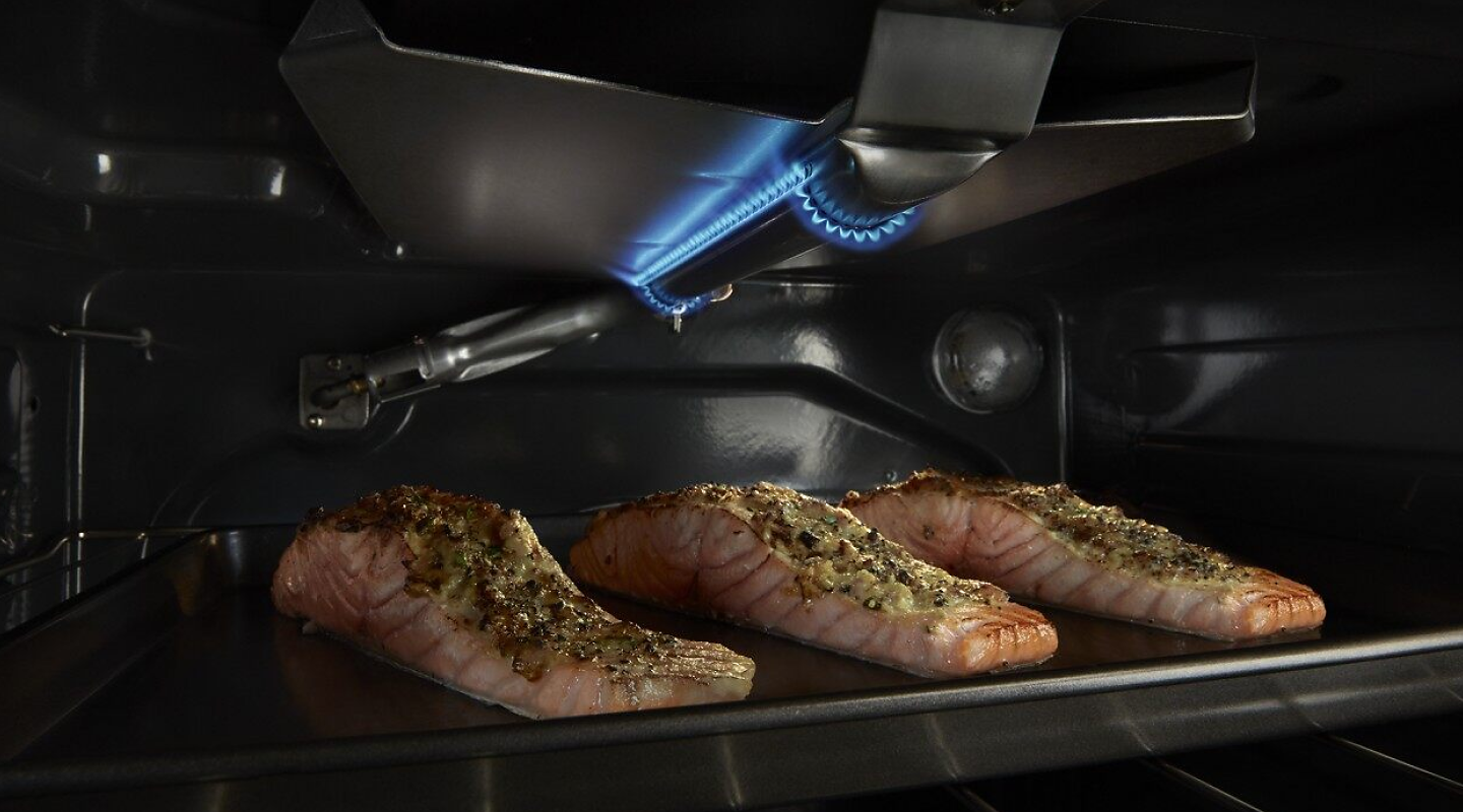 Three salmon filets broiling in an oven.